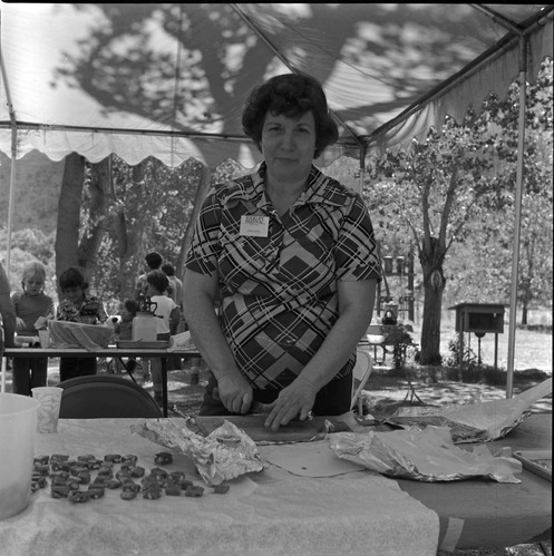 Woman cutting baked goods at the first annual Folklife Festival, Zion National Park Nature Center, September 1977.