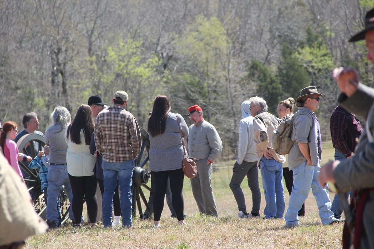 Visitors gather around a living historian in period uniform