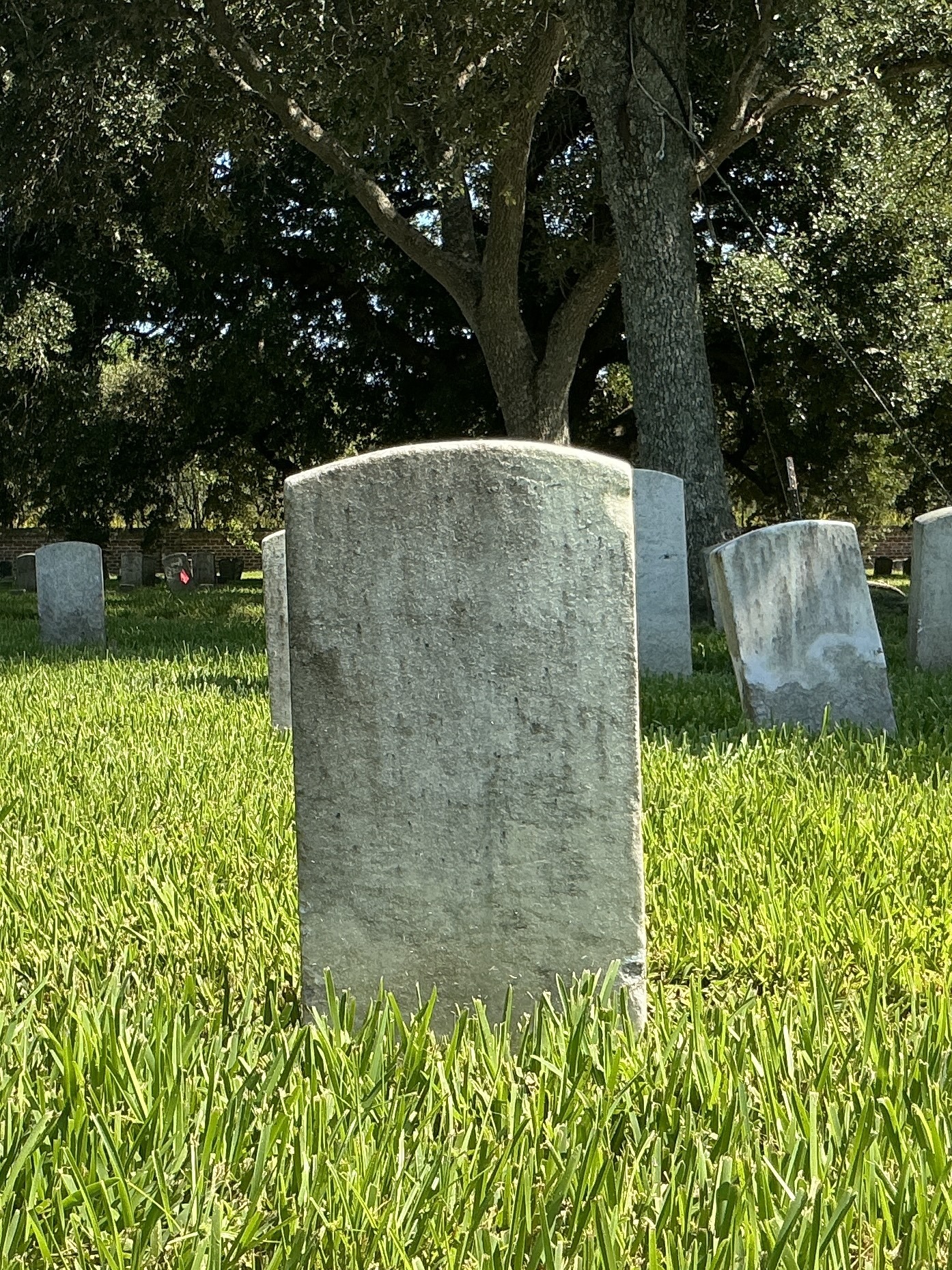 Back of historic upright marble headstone with recessed shield face.