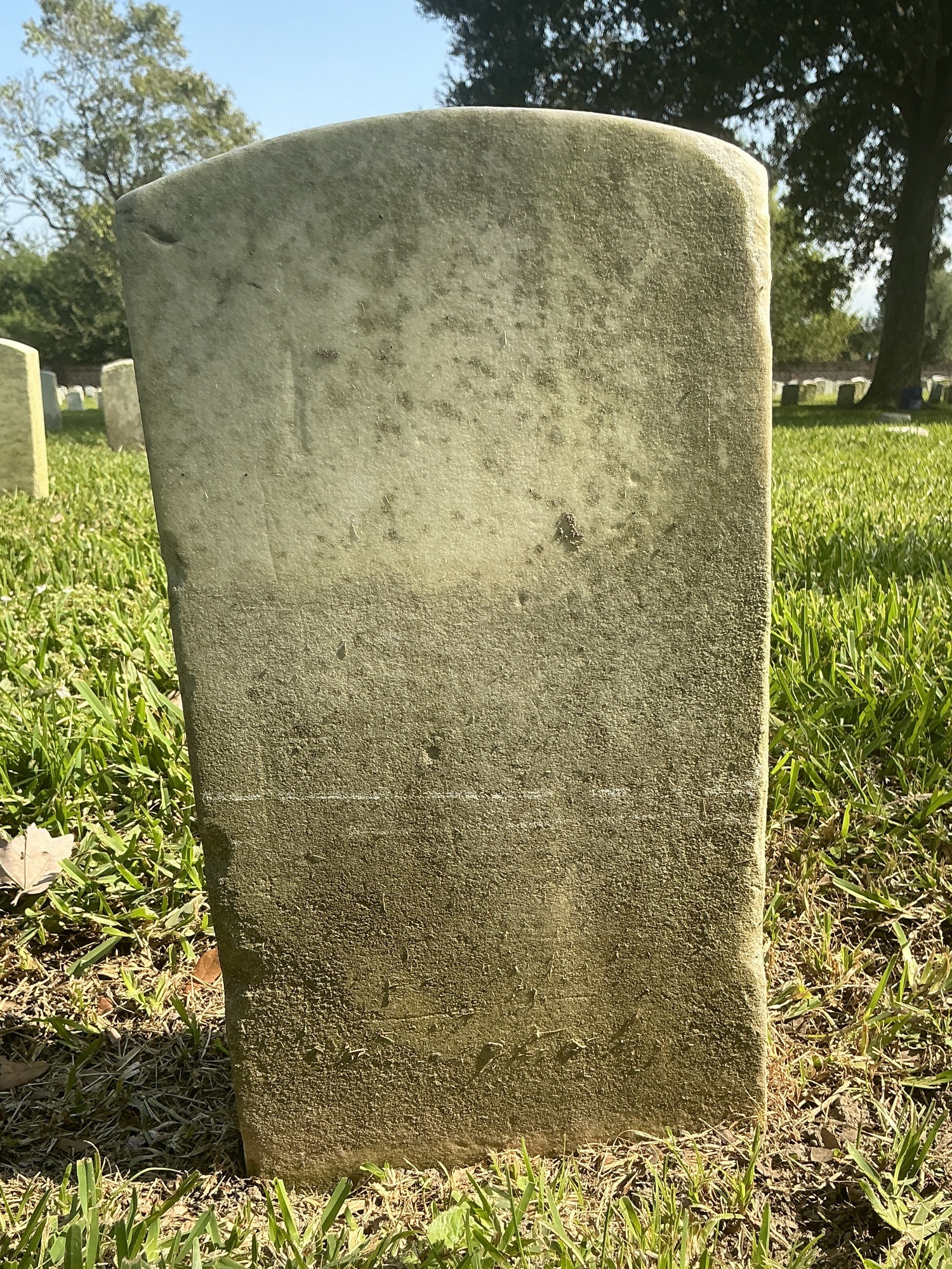 Back of historic upright marble headstone with recessed shield face.