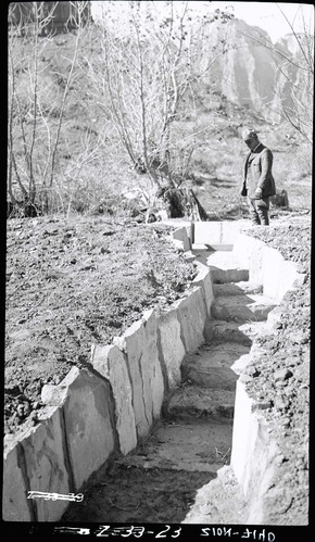 Irrigation ditches with ranger looking at water drops.