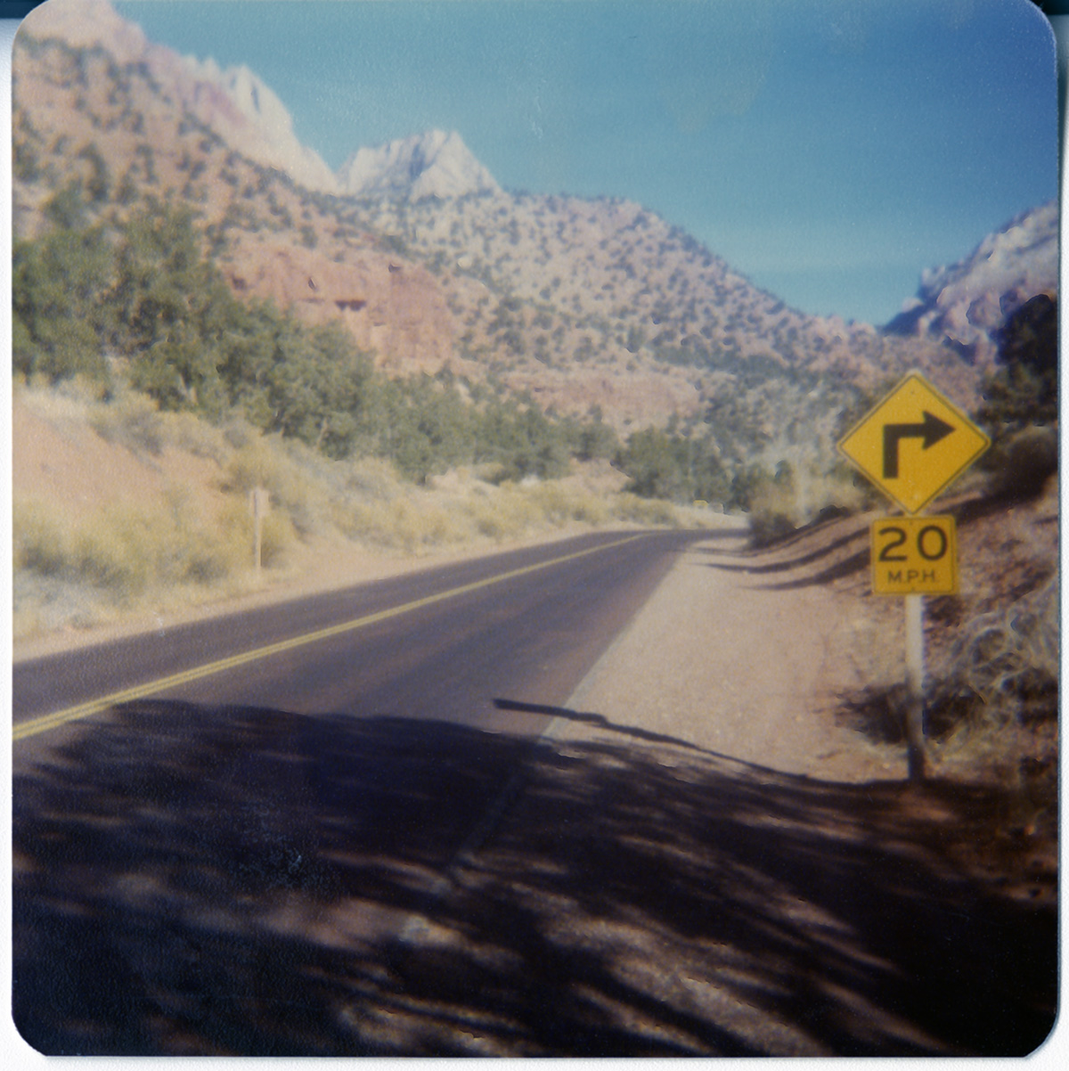 Zion road with Zion landscape in background and with a 'right turn 20mph' sign.