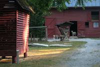 Red barn in foreground with a goat standing in the doorway