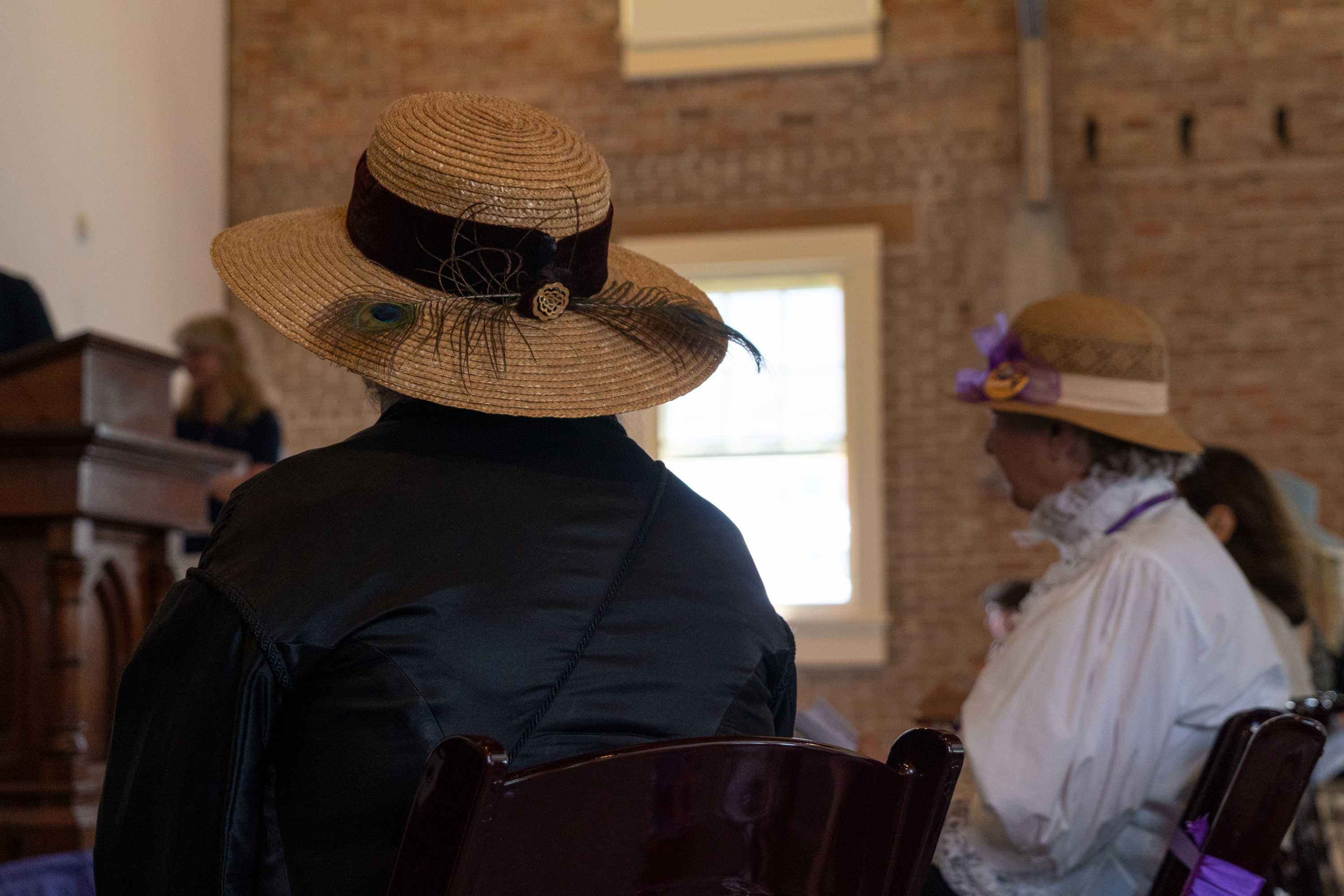 A woman in a hat looks at a stage.