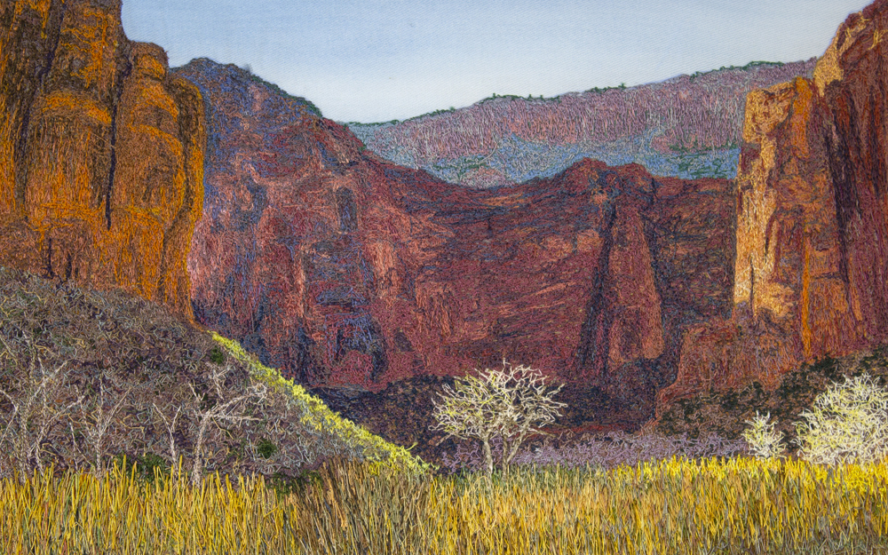 A landscape image created using colored thread and fabric. This view shows the Big Bend area of Zion Canyon. In the foreground, grasses and small trees line the floodplain of the Virgin River. In the middleground, a few sandstone formations jut out into the canyon floor. These formations cast shadows on their surroundings. In the background, massive sandstone cliffs tower over the canyon, showing a rich variety of colors including red, purple, and green.