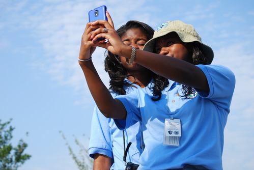 Two YCC members take a picture of themselves using a cell phone. They are outside on a sunny summer day.