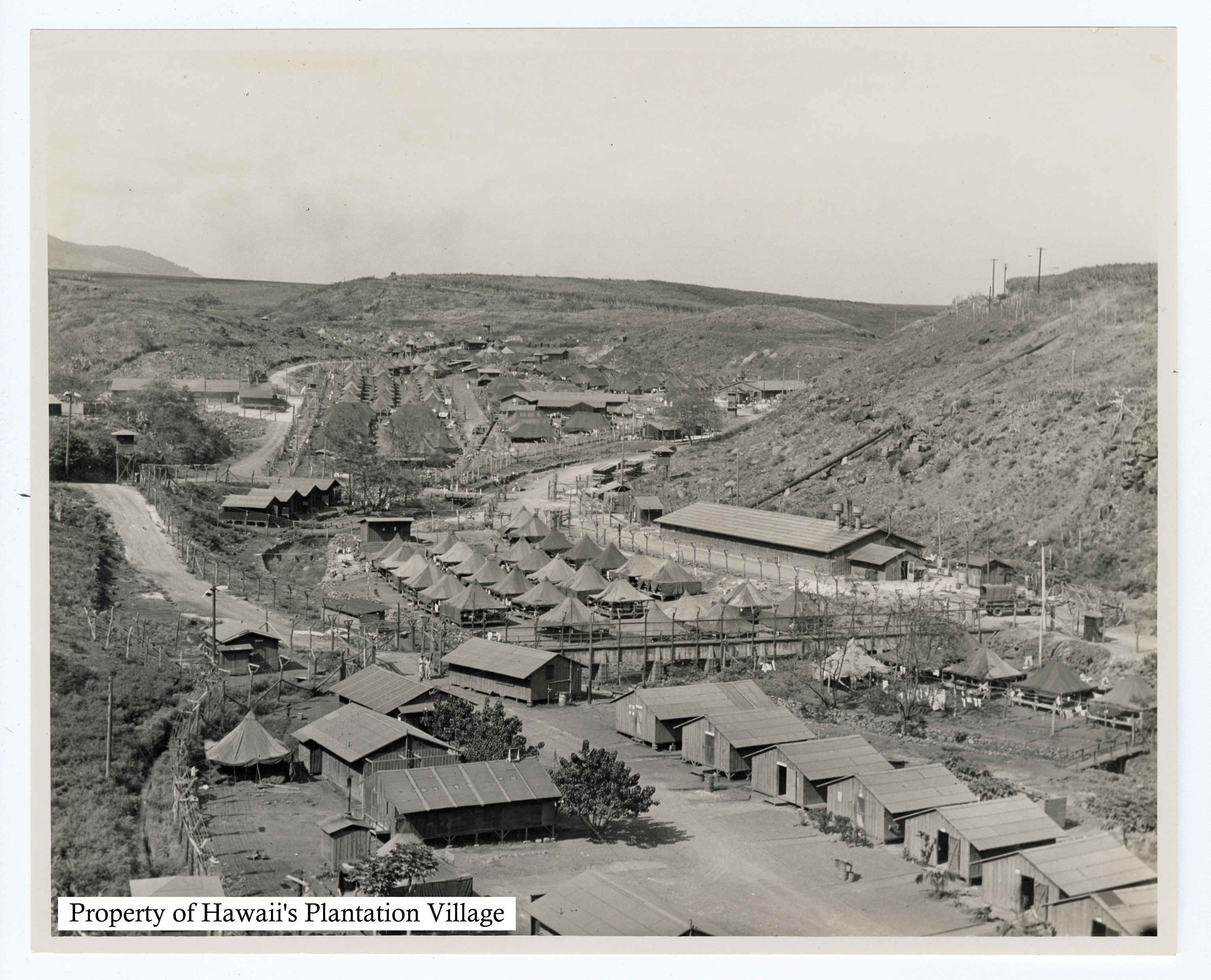 A valley with hundreds of structures, including tents, barracks, and some roads weaving between.