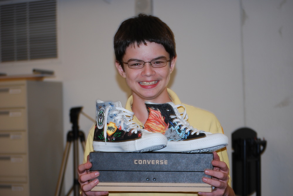 YCC member showing off black shoes he decorated with flames and other brightly colored elements.