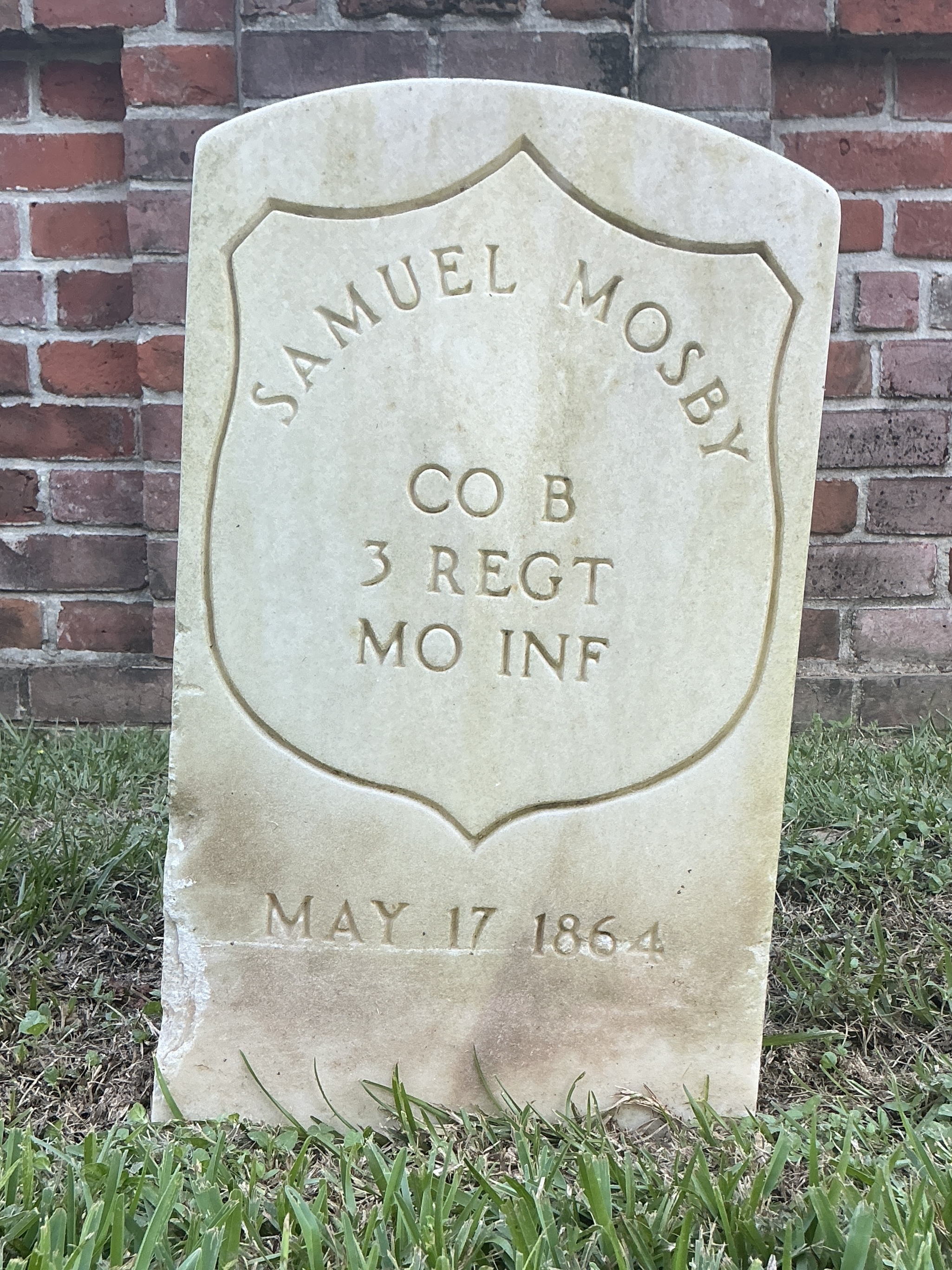 Front of historic upright marble headstone with incised shield face.