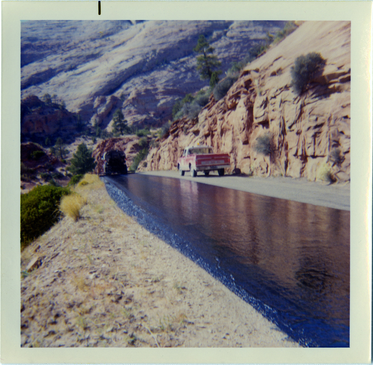 Construction vehicles performing chipsealing on roads.