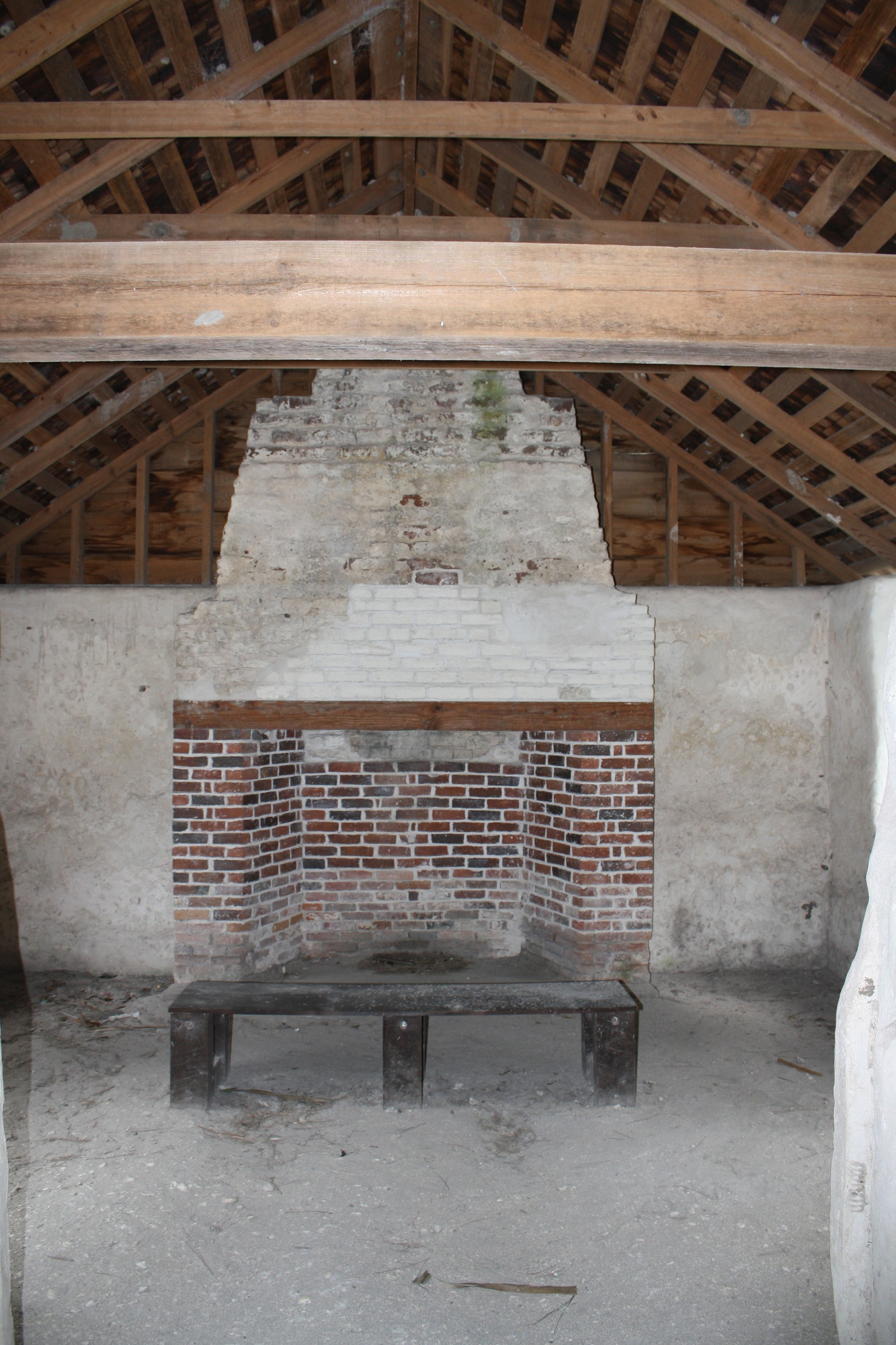 a fireplace of red and white bricks with wood beams overhead 