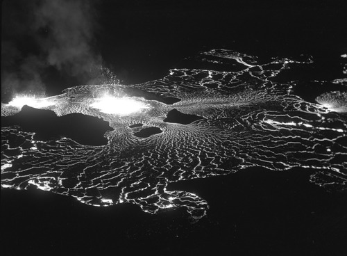 Black and white image of close-up views of several crags surrounded by lava fountains and flows. 