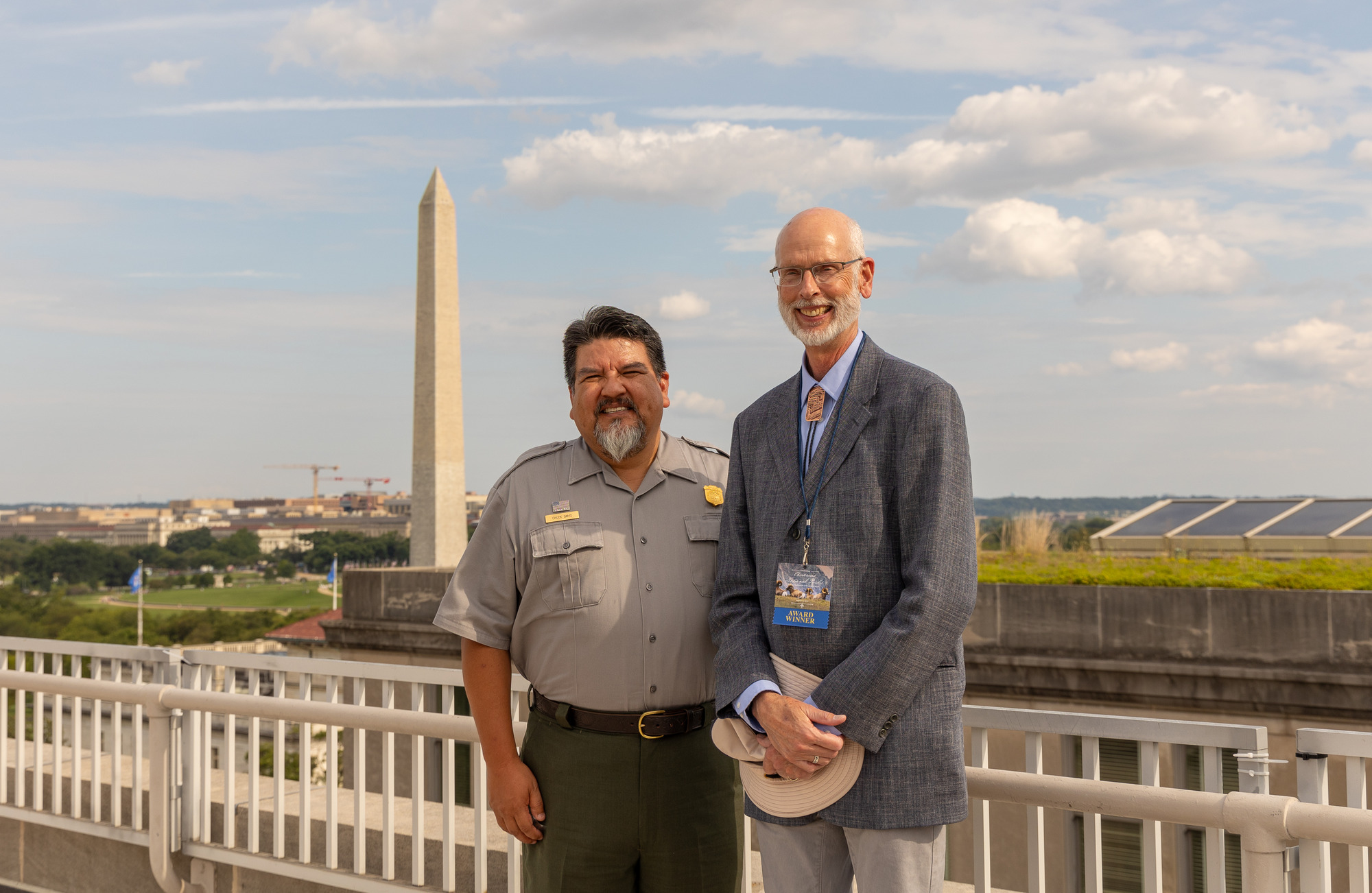 Two men stand in front of the Washington Monument.