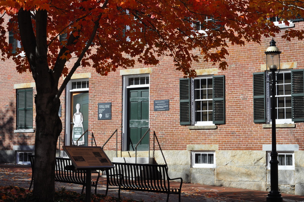 An exterior shot of the Mill Girls and Immigrants exhibit with a tree in the foreground