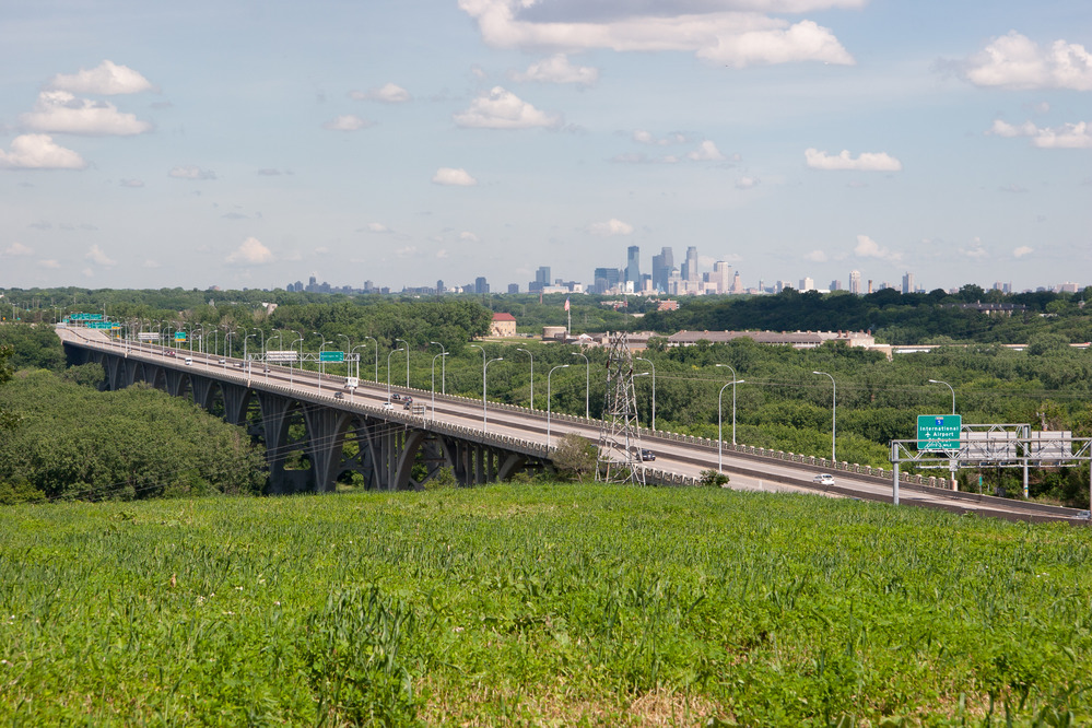 A bridge in the foreground over the river, and also showing the Minneapolis skyline in the background.  