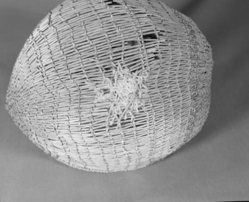 Private Collection. Object: Miwok basket. Dimensions: 9 1/2 x 4 1/2 x 8". Materials: Scraped shoots, split shoots, bracken fern root, and cotton string. Technology: Diagonally twined, up to right slant of turns, alternate rows with alternate slant. 1/3 of way from start of basket end selvage warp rods bent & lashed with additional bundle of rods coiled on top to even out rim contour. Rimstick attached with the aid of an awl lapping on one side. Repair in commericial cotton cordage apparently using a needle which secures short sections of willow sticks much in the manner of Anglo sock darning. Collection History: Purchased at 3 Flags Trading Post, Coleville, CA. with Miwok identification. Catalogued by Craig Bates and Barbara Beroza. Yosemite Collections, National Park Service.