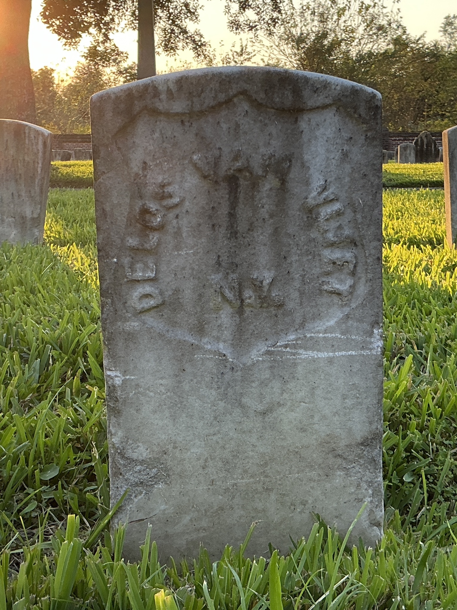 Back of historic upright marble headstone with recessed shield face.