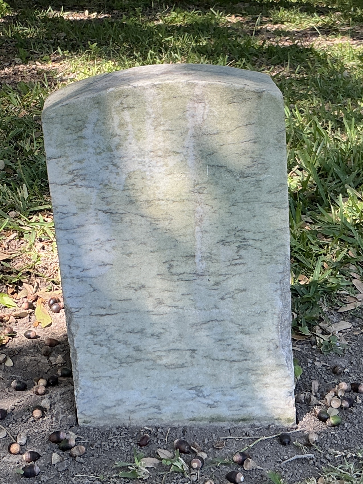 Back of historic upright marble headstone with recessed shield with recessed lettering face.