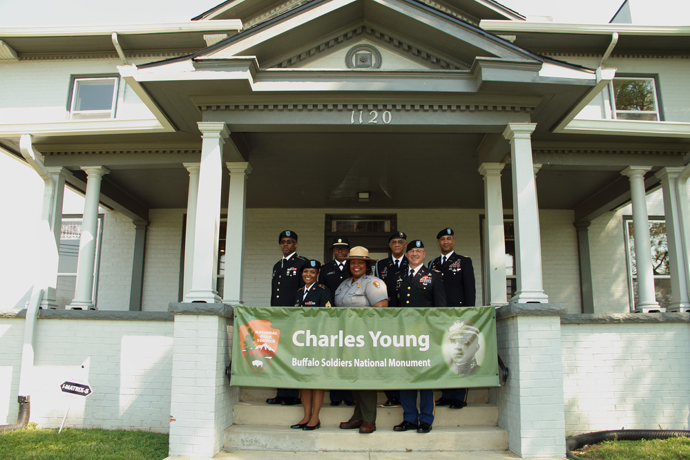 Six ROTC members and one park ranger pose for a photo in front of a banner