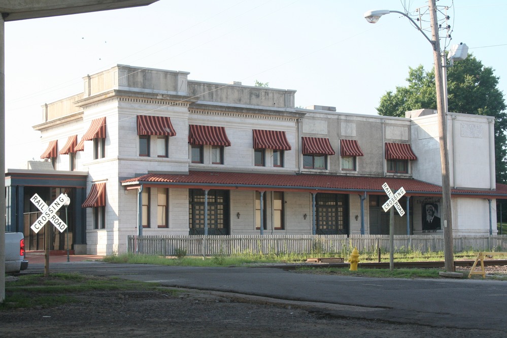 A two-story white stone building with red and white striped window awnings.