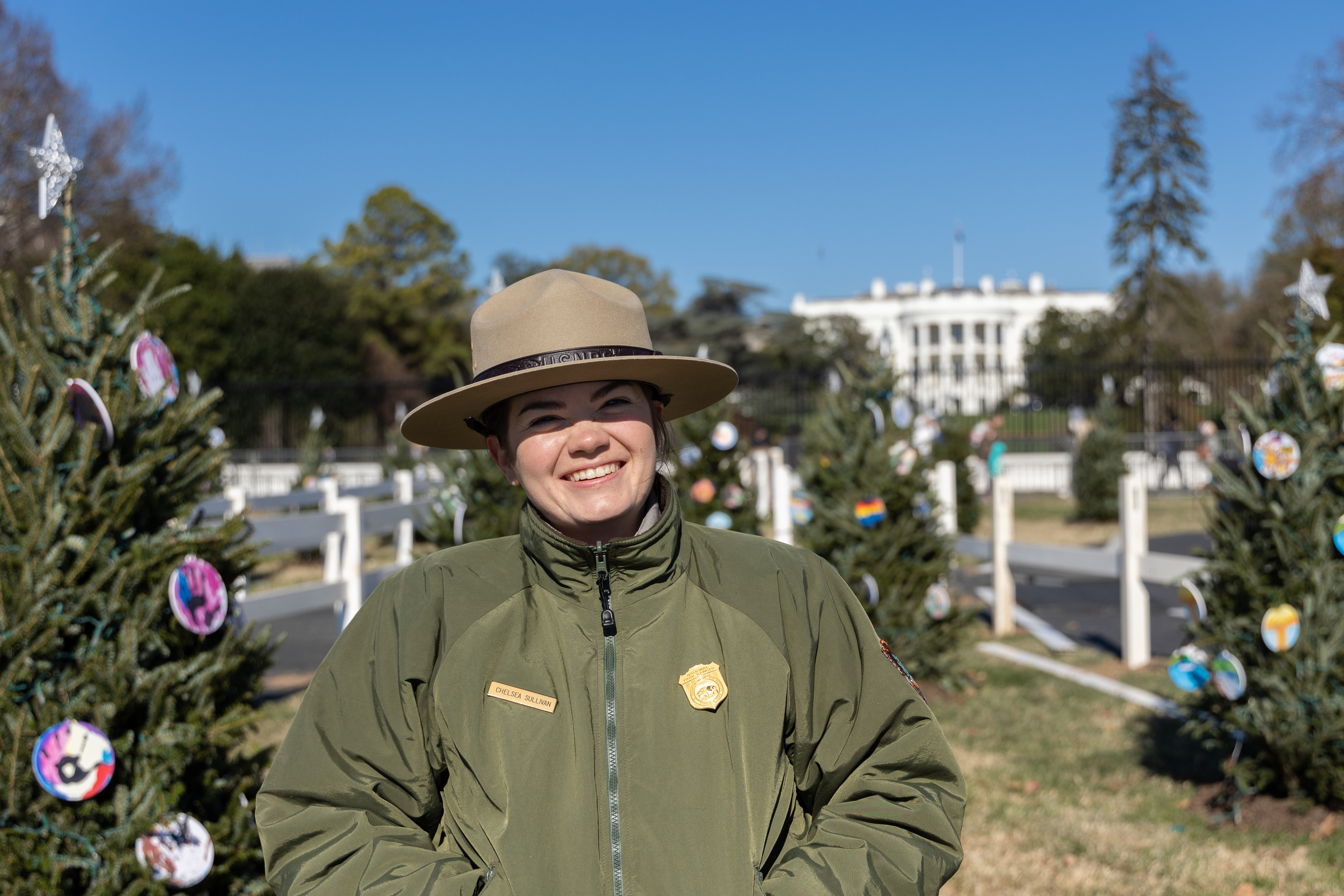 A Park Ranger stands in front of the decorated Christmas trees in front of the White House. 
