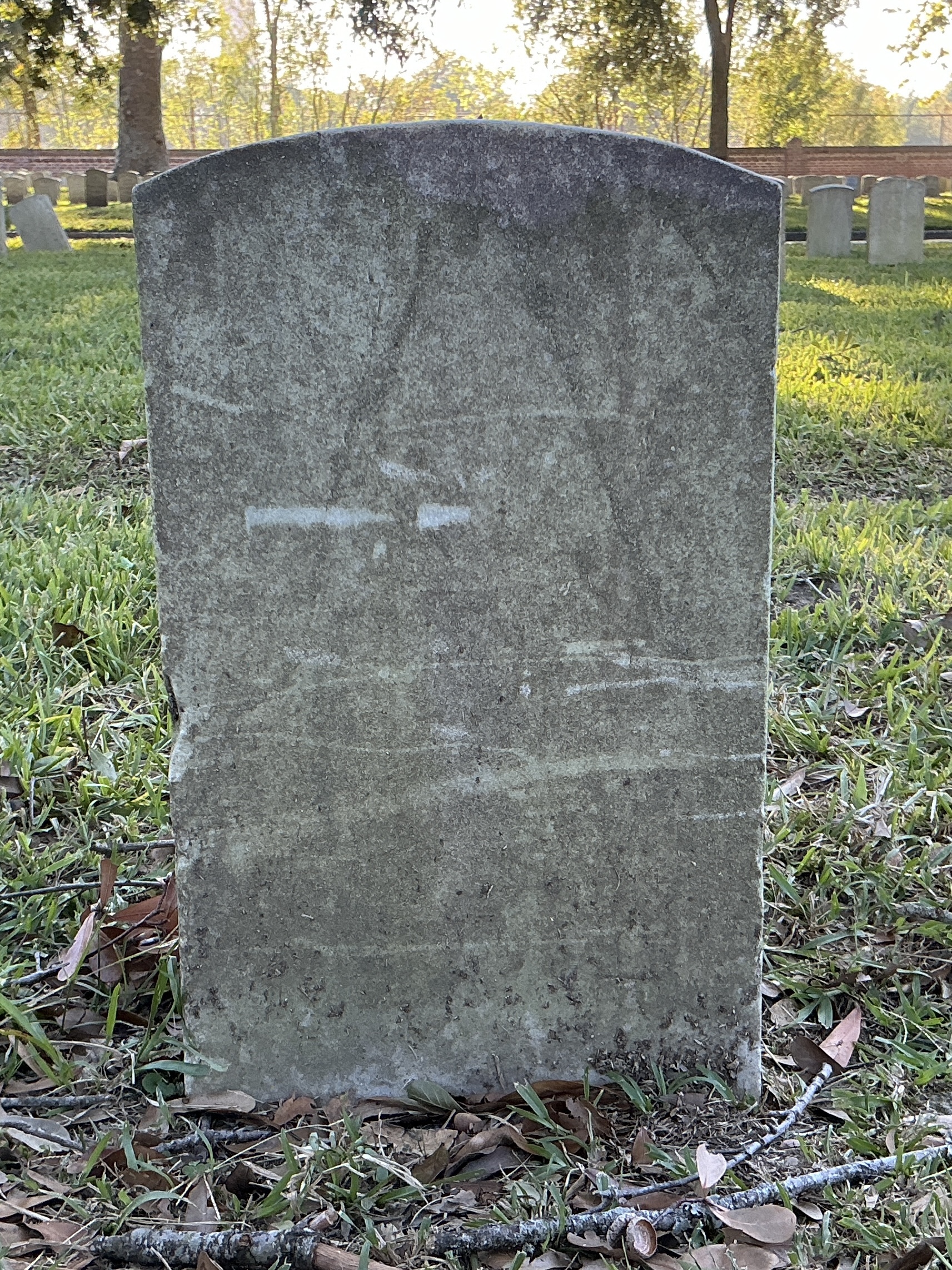 Back of historic upright marble headstone with recessed shield face.