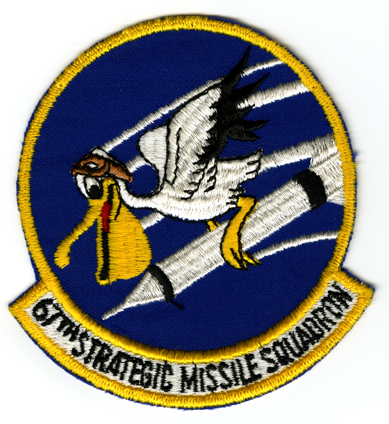 Circular patch with tab on bottom 1/4 edge. Dark blue background with gold trim and a white, black, and yellow sea gull riding a black and white missile. 67TH STRATEGIC MISSILE SQUADRON" in black on white background in tab."
