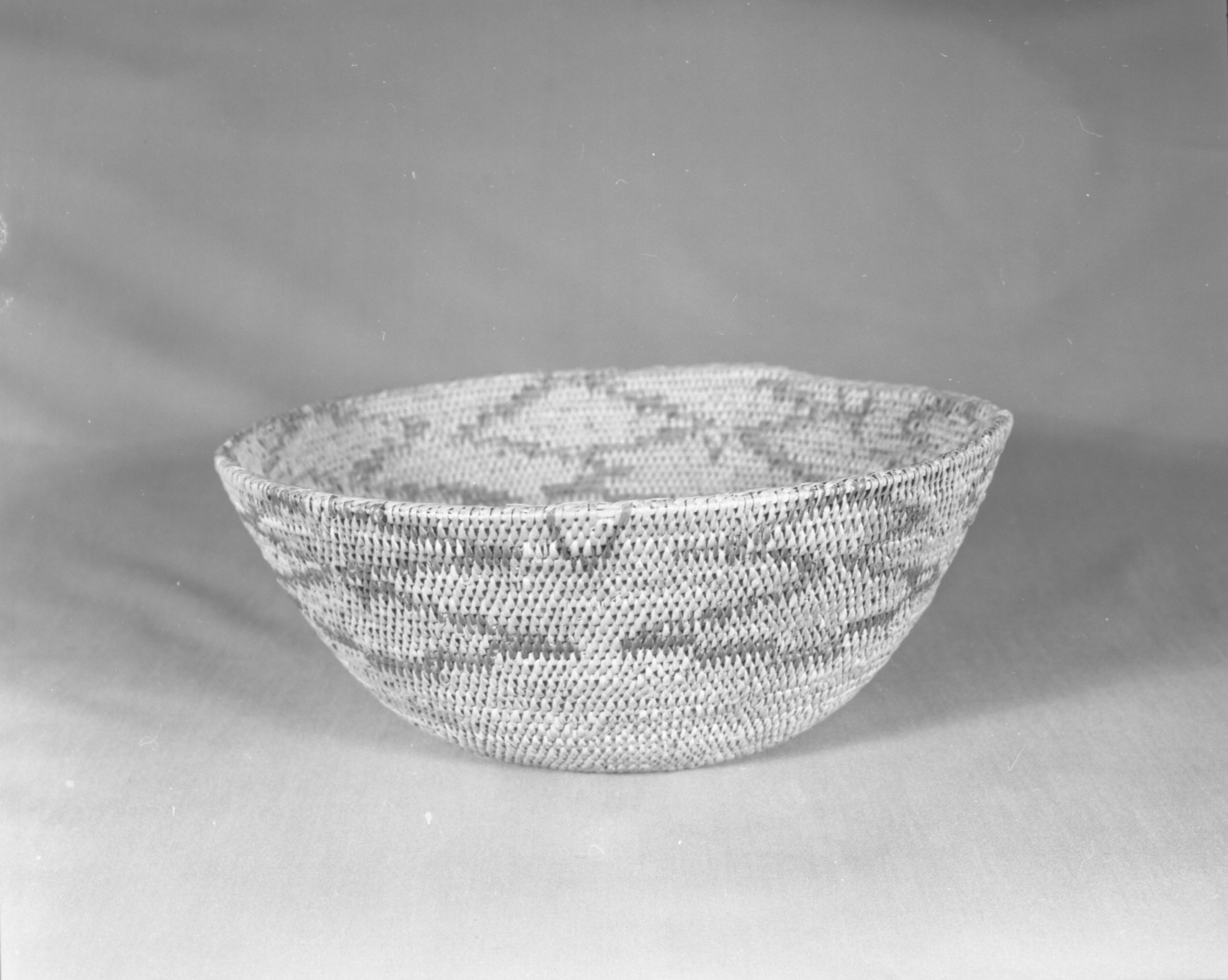 Private Collection. Object: Miwok basket. Dimensions: 11 1/2 x 4 1/2. Materials: Bracken fern, redbud, & bull pine. Technology: Single rod, fag ends trimmed on work face, moving ends trimmed on interior. Leftward coil direction. Bracken fern used in "V" shape design units along top edge. Collection History: Matilda, a Sonora Miwok c. 1920. Photographed by Michael Dixon. Catalogued by Craig Bates and Barbara Beroza. Yosemite Collections, National Park Service.