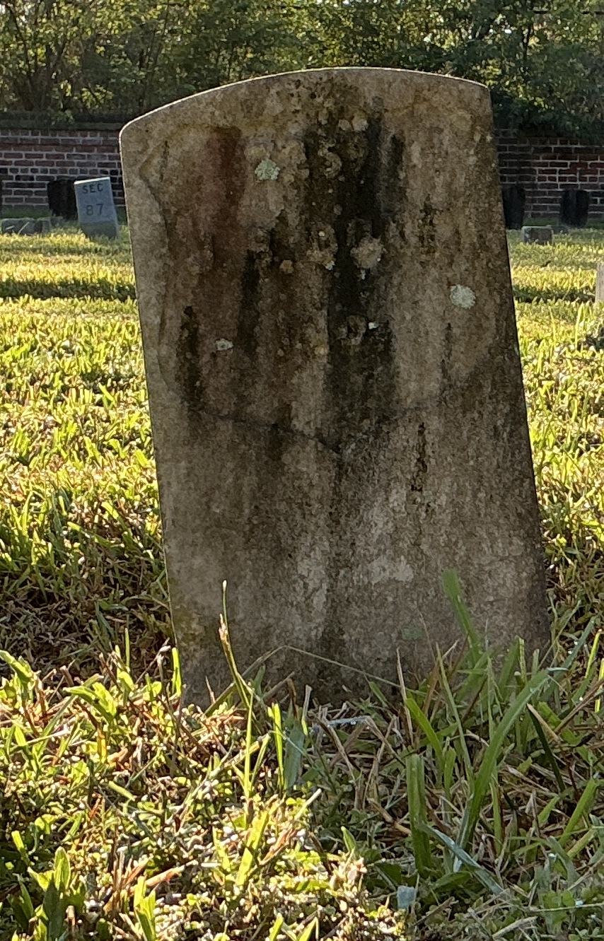 Front of historic upright marble headstone with recessed shield face.
