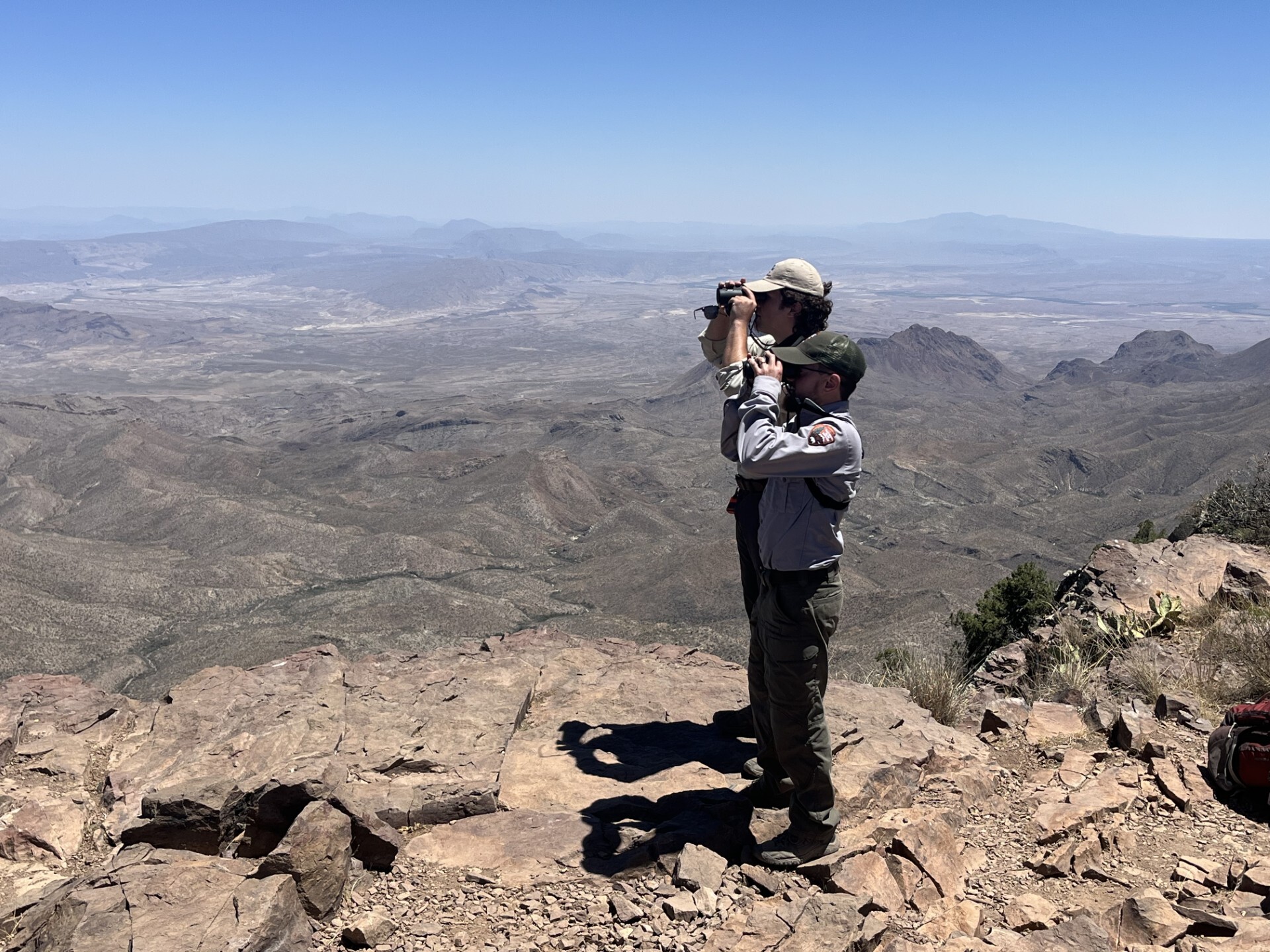 Jeremiah Wright and colleague using binoculars on mountain peak