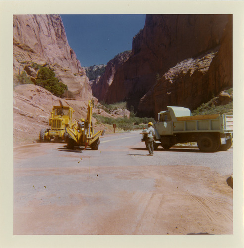 Man working alongside tractors on shoulder work along route 2 parking areas.