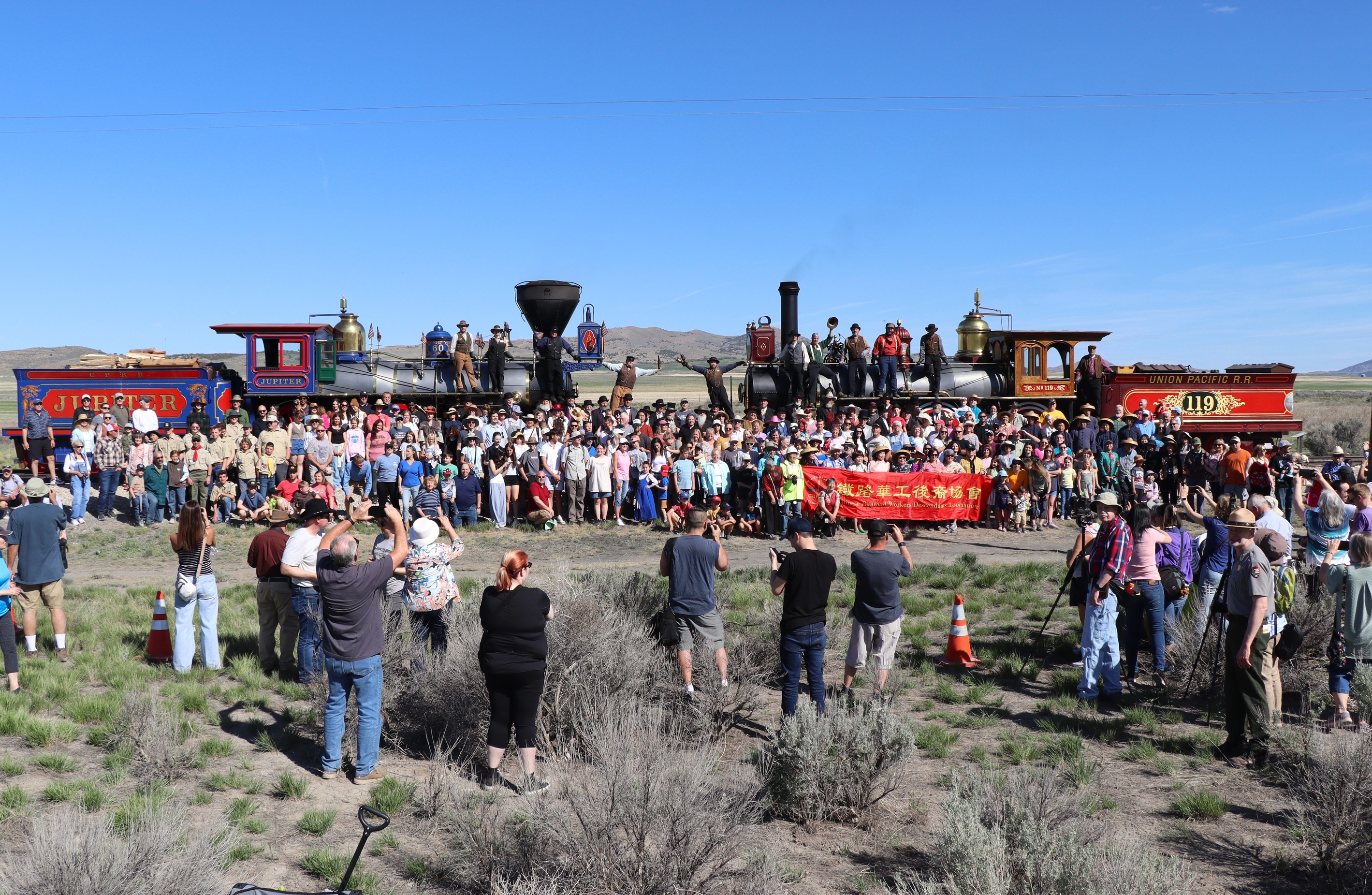 People gathered around two vintage Locomotives to recreate the Historical Champagne photo.