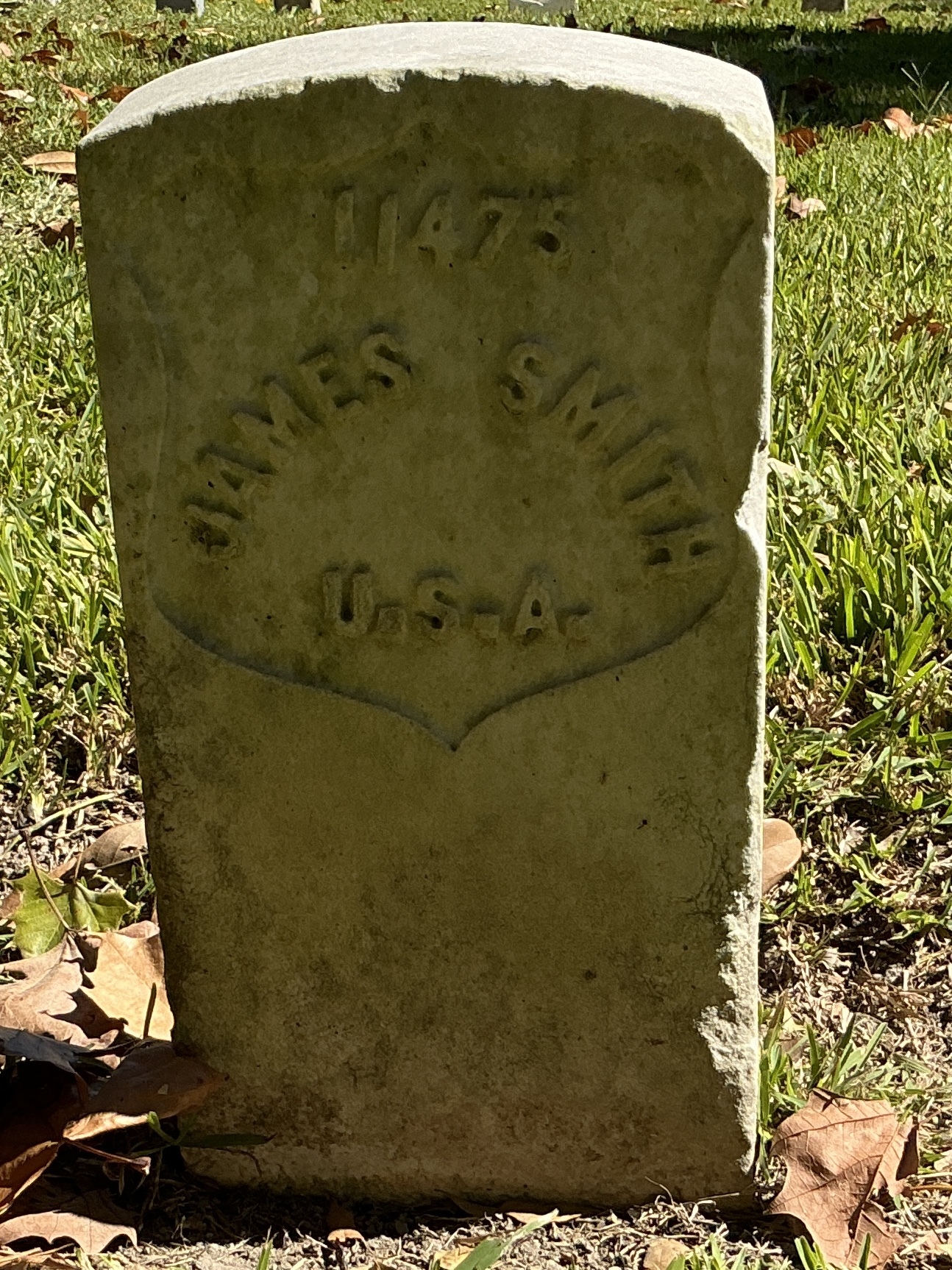 Front of historic upright marble headstone with recessed shield face.