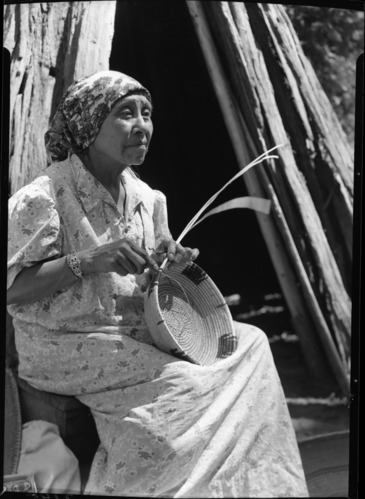 Lucy Telles weaving a basket, back of Museum.