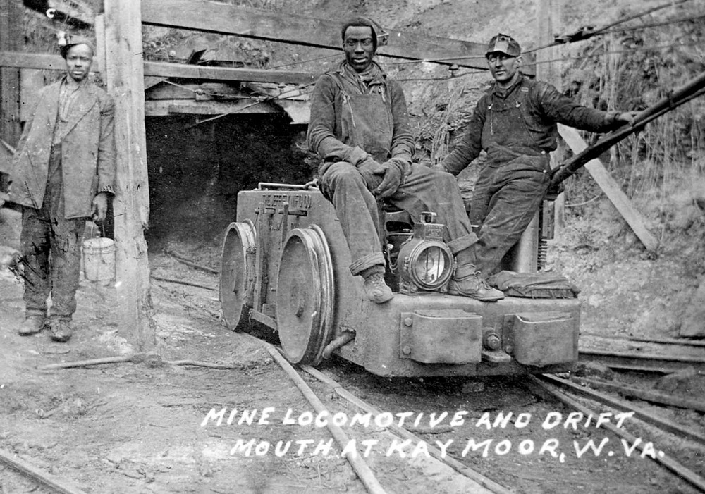 coal miners pose on an electric mine locomotive
