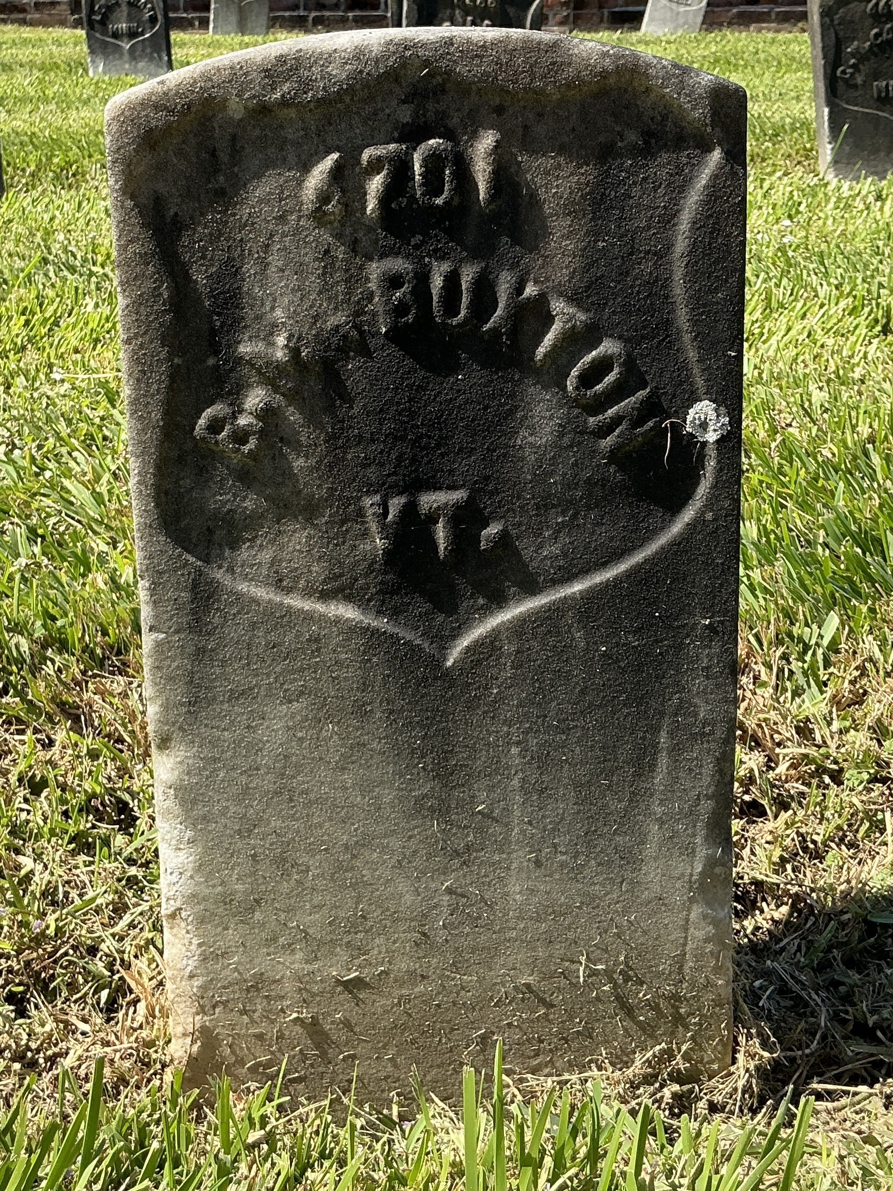 Front of historic upright marble headstone with recessed shield face.