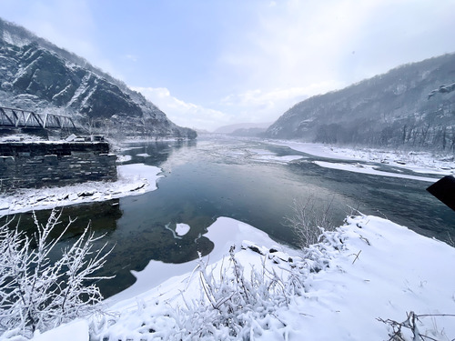 View of the confluence of the Potomac River and the Shenandoah River at Harpers Ferry National Historical Park. The dark, icy water of the Potomac River flows through a large gap in the Blue Ridge Mountains.