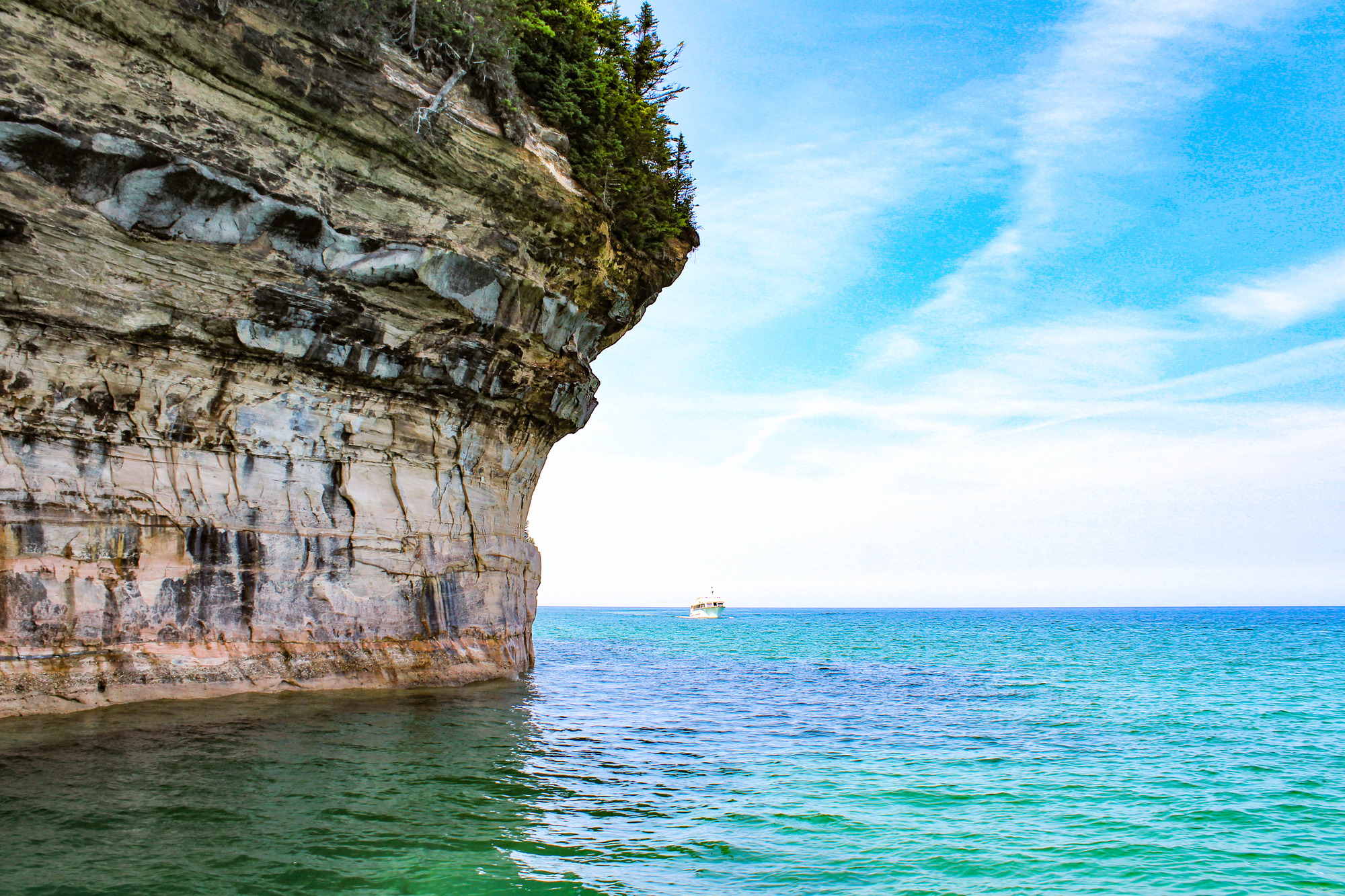 Passenger boat on a lake near a cliff 