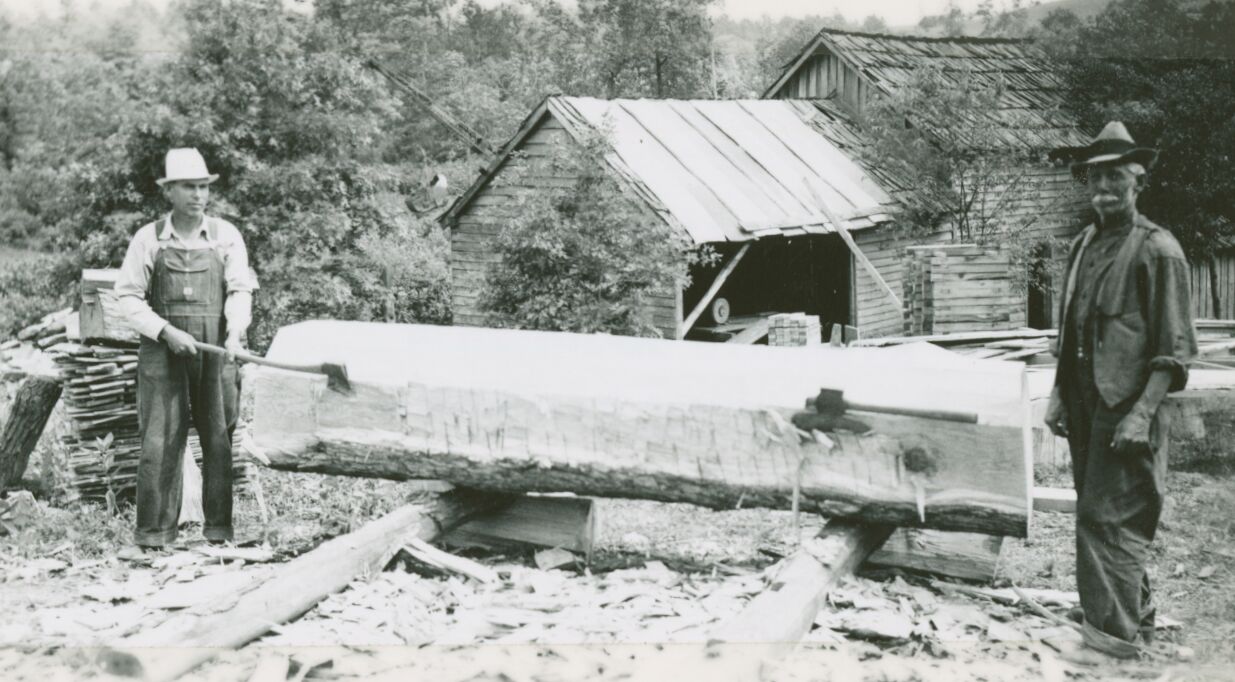 Men standing next to a large timber