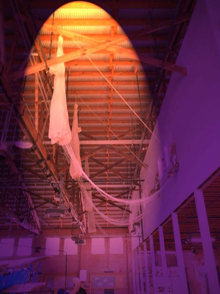 Photo of a World War II-era parachute hanging in a museum filtered to appear purple and yellow