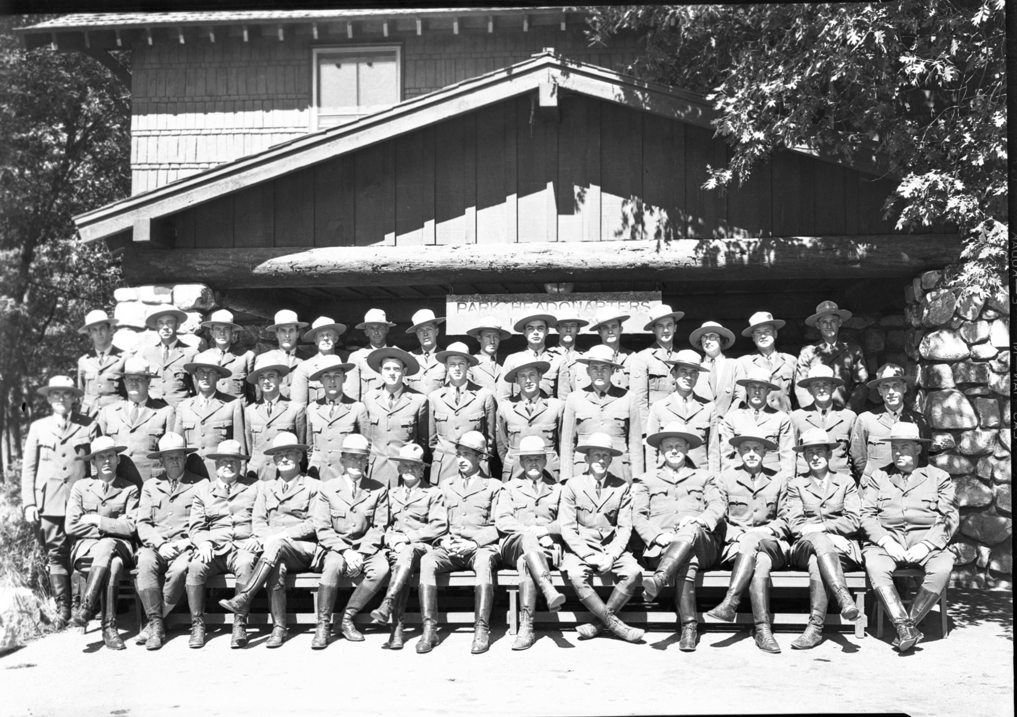 July 4th Conference of Ranger Force, in front of Admin. Building. Top Row: Frank Anderson, J. Minter, Odin Johnson, Don Bryan, Grover Caster, Vernon Lowery, Mitch Akins, Otto Brown, Holmes Miller, Ted Barnett, Gene Burns, Jack Scholl, Mrs. Hazel Whedon, Lloyd Finch, Dewey Winder. Middle Row: H. Rodeck (photogr:), Whedon, Archie Westfall, Damon Eckley, Harry During, Gerald E. Mernin, Ferd. Fletcher, L. Wieland, Russ Huse, Elwin Heller, W. K. Merrill, L. Farwell, Homer B. Hoyt. Lower Row: John Bingaman, Henry A. Skelton, Chas. F. Adair, Gus Eastman, Billy Nelson, Carl Danner, Frank A. Kittredge - NPS Chief Engineer, Supt. C. G. Thomson, Chief Ranger F. S. Townsley, Assist. Chief J. Wegner, Oscar Irwin, Ernie Reed.