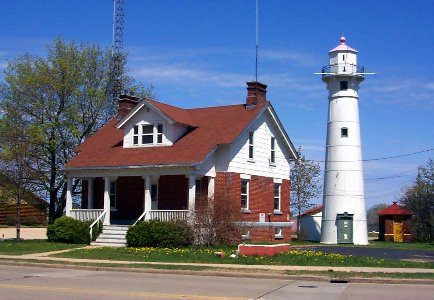 two story house with front porch. Lighthouse is behind it.