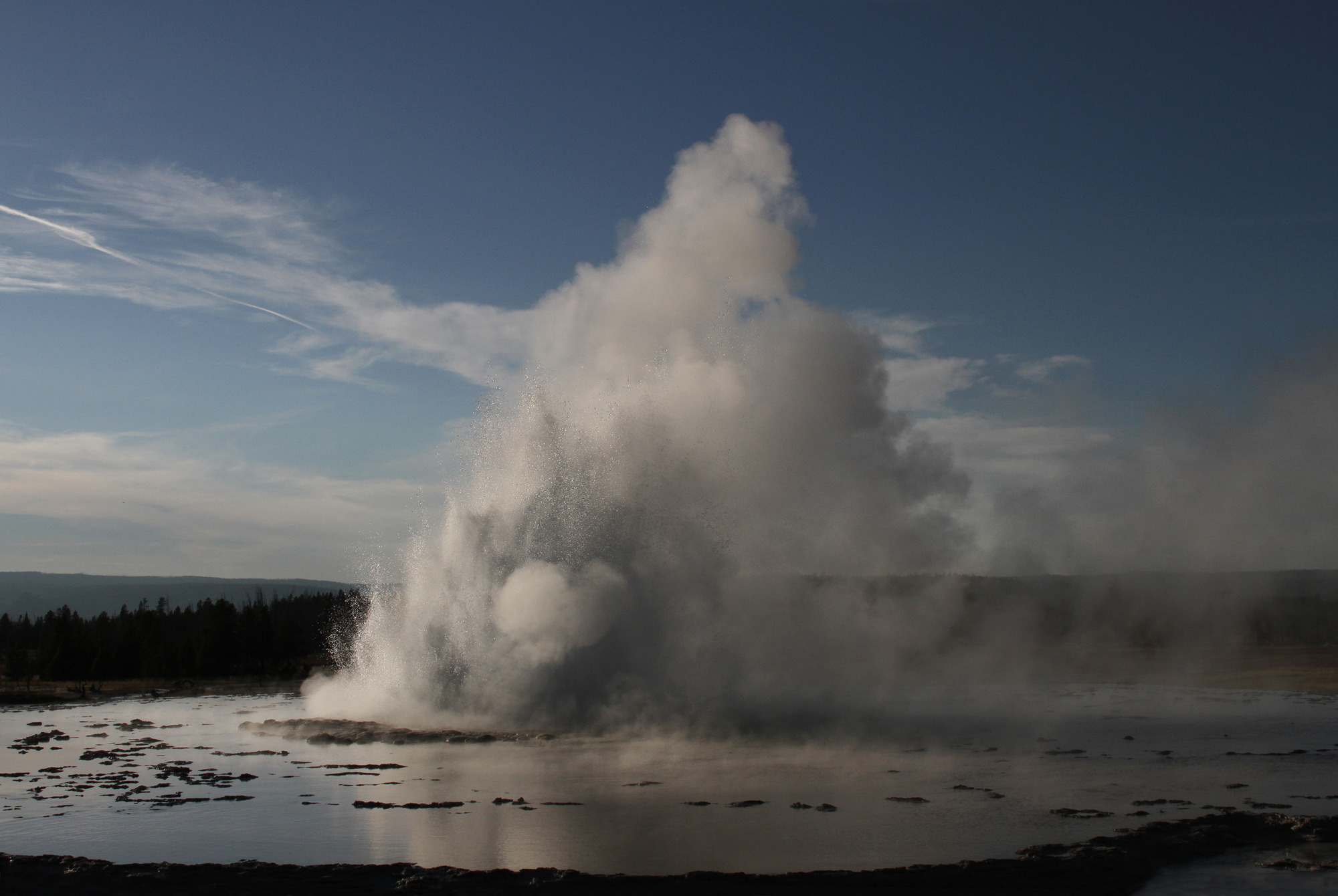 A wide column of water erupts from a pool surrounded with terraces.