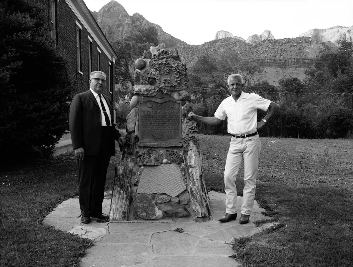 Centennial Preparation Committee members Springdale Mayor Austin Excell and Bishop Alvin Hardy pose next to 'Discovery of Zion Canyon' commemorative plaque.