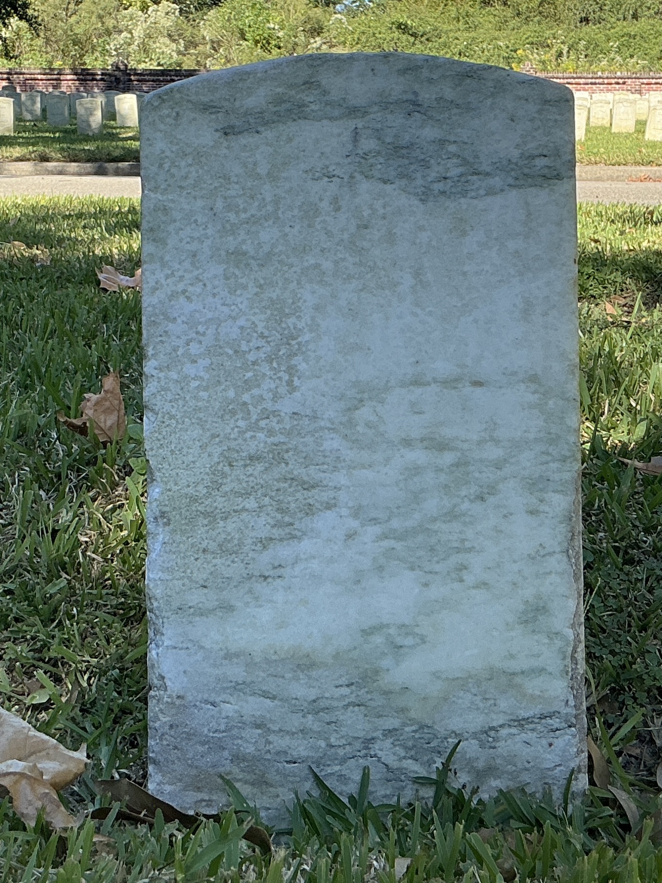 Back of historic upright marble headstone with recessed shield with recessed lettering face.