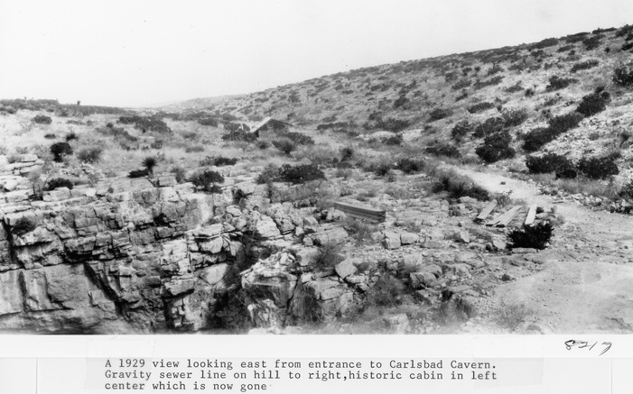 A 1929 view looking east from entrance to Carlsbad Caverns. Gravity sewer line on hill to right. Historic cabin in left center which is now gone.