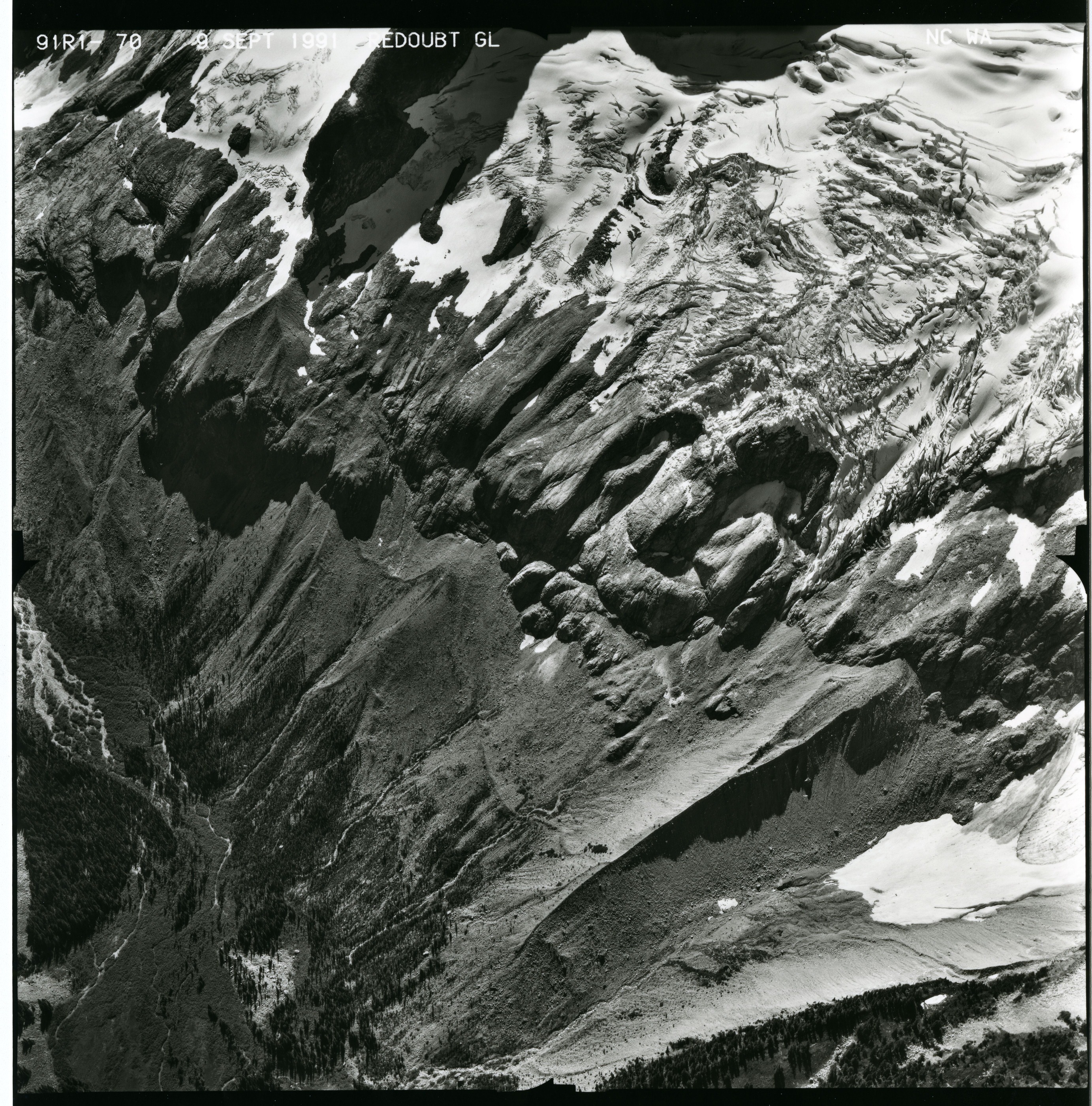 Black and white aerial photograph of glaciated mountain peaks and valleys.
