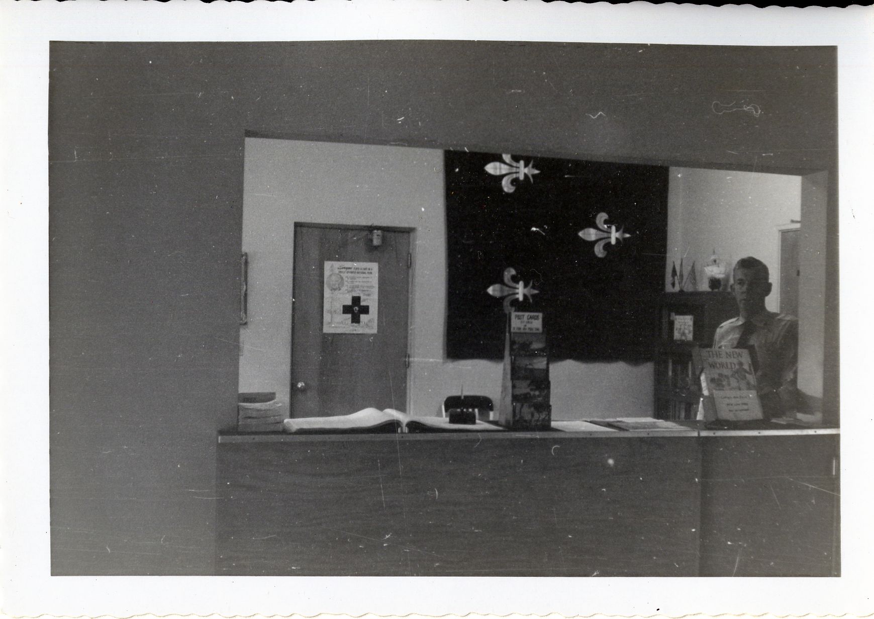 a park ranger standing behind a desk on the wall hangs the historic French flag 