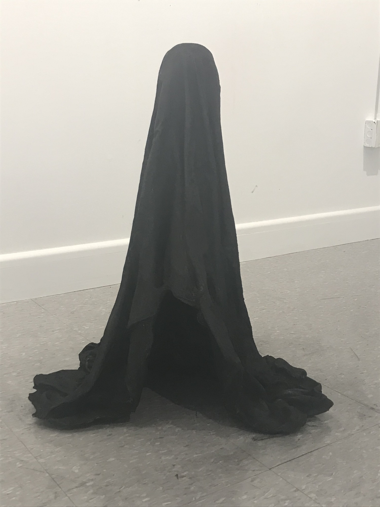An iron sculpture resembling a ghost made from a black sheet.