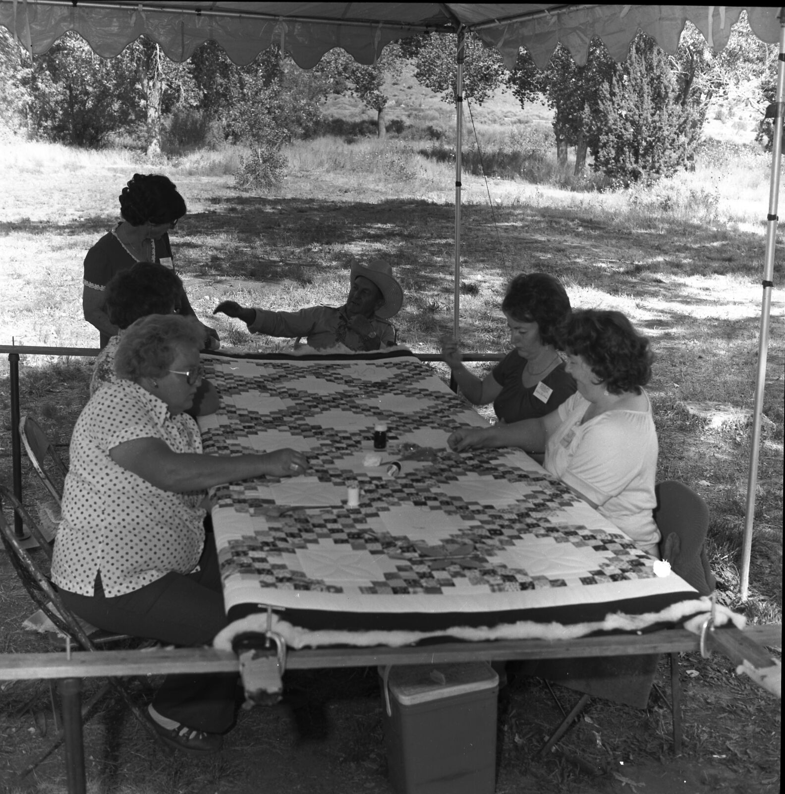 Vilo DeMille quilting with women and man at the first annual Folklife Festival, Zion National Park Nature Center, September 1977.